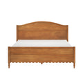 Solid wood panel bed frame with curved headboard, scalloped apron, turned tapered legs and warm honey wood finish — rustic farmhouse bedroom centerpiece