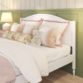 Girls' bedroom with white wooden bed, plush teddy bear, pink and cream pillows, floral bolster, bedside lamp and green paneled accent wall