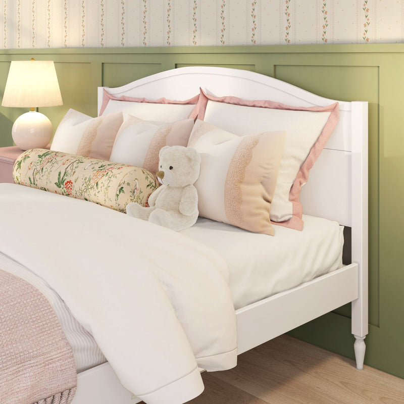 Girls' bedroom with white wooden bed, plush teddy bear, pink and cream pillows, floral bolster, bedside lamp and green paneled accent wall
