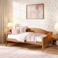 Pink girls' bedroom with wooden daybed, soft pink bedding, floral wallpaper, framed poodle artwork, teddy bear and bedside lamp