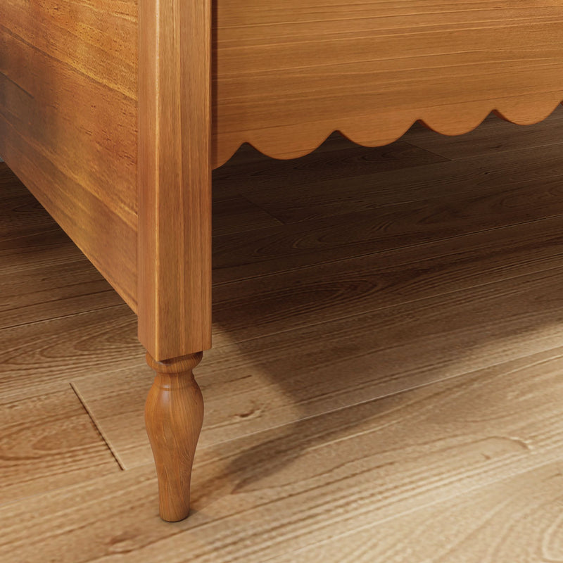 Close-up of oak wooden bed frame with turned leg and scalloped skirtboard on dark hardwood floor