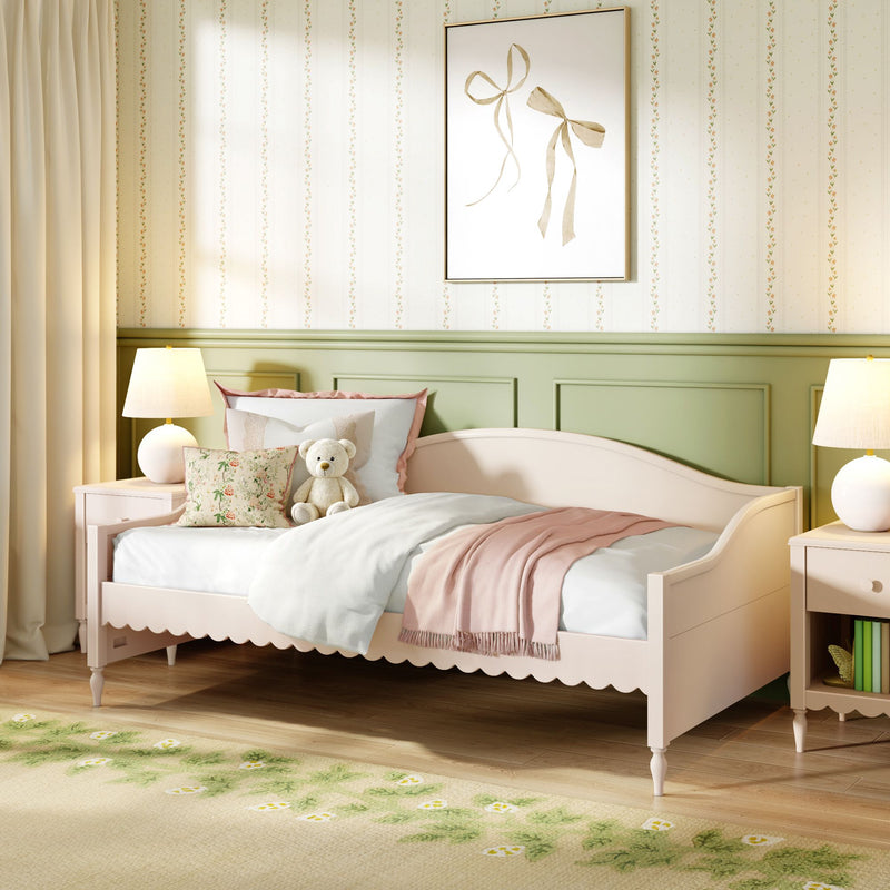 Cozy pastel kids' bedroom with pink daybed, plush teddy bear, floral throw pillow, green wainscoting, framed bow wall art and warm bedside lamps