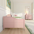 Pastel pink girl's bedroom with scalloped pink bed, matching pink dresser and lamp, floral striped wallpaper, green throw and hardwood floor