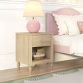 Light wood nightstand with drawer and wicker basket on open shelf, pink round lamp beside scalloped pink twin bed in a pastel kids' bedroom