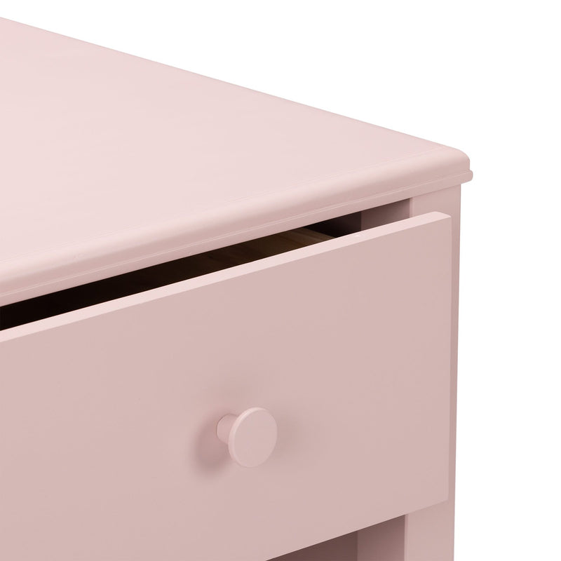 Close-up of pink wooden dresser drawer with round knob and matte finish, modern nursery storage chest