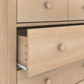 Light maple dresser with a partially open drawer, round wooden knobs and metal slide rails — modern bedroom storage chest of drawers
