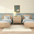Cottage-style twin bedroom with light wood beds and dresser, pastel blue wainscoting, floral wallpaper, swan painting, bedside lamp and white area rug