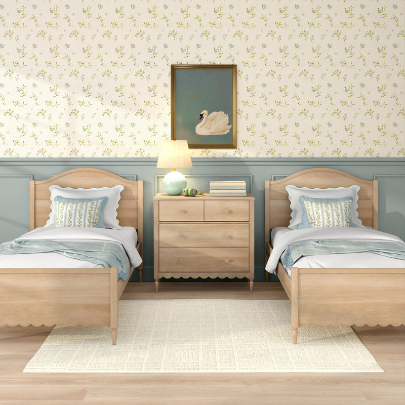 Cottage-style twin bedroom with light wood beds and dresser, pastel blue wainscoting, floral wallpaper, swan painting, bedside lamp and white area rug