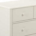 Close-up of cream painted wood dresser drawers with round knob and smooth beveled top — modern bedroom furniture