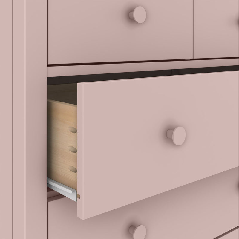 Matte pink dresser with a partially open drawer showing wooden interior, visible joinery and metal drawer slides — modern bedroom or nursery storage
