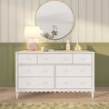 White nursery dresser with round gold mirror, pink lamp, floral wallpaper, green wainscoting and wooden house decor