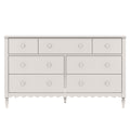White wooden six-drawer dresser with round knobs, scalloped apron and turned tapered legs, farmhouse-style bedroom storage chest