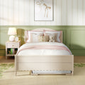 Children's pastel bedroom with white bed, pink bedding, floral throw pillow, teddy bear, green wainscoting, bedside lamp and ribbon wall art