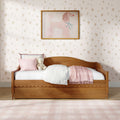 Cozy girls bedroom with wooden daybed, pastel pink bedding and throw, plush teddy bear, floral wallpaper and framed pink poodle wall art
