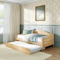Wooden trundle daybed in a light-filled pastel bedroom with floral wallpaper, mint wainscoting, gold-framed swan print, cream curtains and blue throw