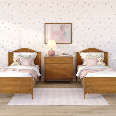Pastel pink twin girls bedroom with wooden beds, floral wallpaper, pink bedding, teddy bears, wooden dresser, lamp and poodle wall art