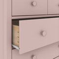 Pink painted dresser with an open drawer revealing natural wood dovetail joints and metal drawer slides, modern bedroom storage