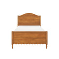 Wooden bed frame with arched headboard, scalloped footboard and turned legs in warm honey finish on white background