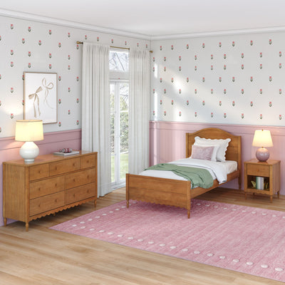 Girls bedroom with wooden twin bed, pink wainscoting, floral wallpaper, white curtains, wooden dresser, kids room decor