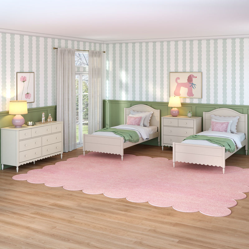 Children's pastel twin bedroom with white beds, pink scalloped rug, green wainscoting, striped wallpaper, floral and poodle wall art, dresser and bedside lamps