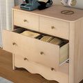 Light wood bedroom dresser with brass knobs and open drawer revealing folded blankets, retro instant camera and headphones on top