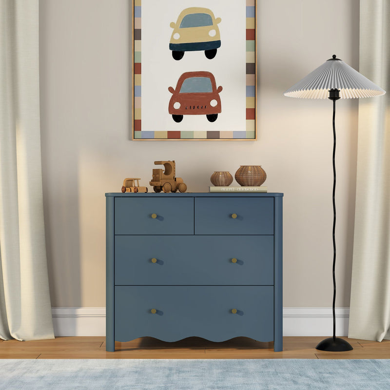 Blue kids dresser for nursery storage with wooden toy cars and woven baskets on top, framed car wall art, pleated floor lamp and neutral curtains on light hardwood floor