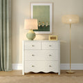 White dresser styled with green ceramic table lamp, framed duck artwork, vintage yellow radio, gold floor lamp and green curtain