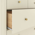 Cream modern dresser with gold knobs and a partially open wooden drawer revealing metal drawer slide, bedroom storage furniture