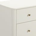 Close-up of modern white nightstand with rounded top edge, cream lacquer finish and brass drawer knob, minimalist bedroom dresser storage