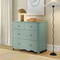 Teal four-drawer dresser with gold knobs and scalloped base topped with a brass dome lamp, woven basket and books in a bright bedroom corner beside sheer curtains and a black wavy floor lamp