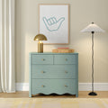 Modern minimalist interior with mint green chest of drawers, gold dome table lamp, pleated floor lamp, woven basket and framed shaka hand artwork on a beige wall