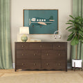 Dark walnut 6-drawer dresser styled in modern bedroom with teal airplane wall art, green ceramic table lamp, wireless headphones and fiddle leaf fig plant
