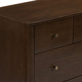 Close-up of a dark brown wooden dresser corner highlighting smooth wood grain finish and a round brass drawer knob