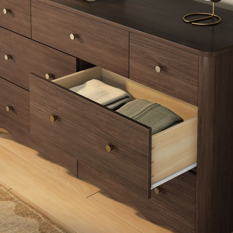 Dark walnut bedroom dresser with a partially open drawer revealing neatly folded sweaters, brass knobs and modern rustic storage on a hardwood floor