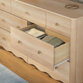 Light wood bedroom dresser with an open drawer showing neatly folded clothes, brass knobs and scalloped base—modern wooden chest of drawers for bedroom storage and organization