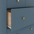 Blue dresser with gold knobs, open drawer revealing wooden interior and metal slide, modern bedroom storage solution