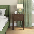 Walnut nightstand bedside table beside green upholstered bed with ceramic lamp, white alarm clock and matching green curtains — modern bedroom decor