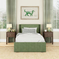 Green upholstered bed with matching headboard, gingham pillows and white bedding in a cozy modern bedroom with wood nightstands, table lamps, green curtains, framed dog watercolor art, large windows and natural jute rug