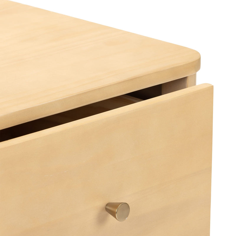 Close-up of a light maple wood dresser drawer with rounded edge and round brushed brass knob