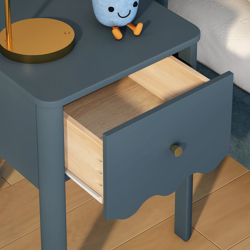 Blue nightstand with open natural wood drawer and brass knob, gold lamp and plush toy on hardwood floor, modern nursery bedroom decor