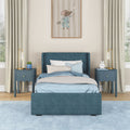 Modern navy blue upholstered twin bed with light blue bedding, matching blue nightstands and gold bedside lamps in a cozy kids bedroom with mouse wall art and pale blue rug