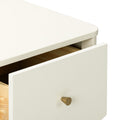 Close-up of cream-painted wooden dresser with a partially open drawer and brass cone knob, minimalist bedroom storage