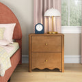 Wooden two-drawer bedside table nightstand with brass knobs, white dome table lamp and blue alarm clock next to coral upholstered bed and pink curtains in modern bedroom