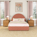 Blush pink bedroom with rounded terracotta upholstered bed, pastel bedding, wooden nightstands, brass lamps, pink curtains and floral wall art