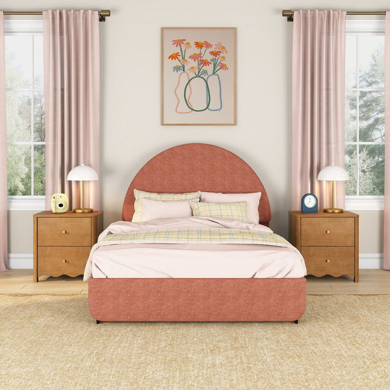 Blush pink bedroom with rounded terracotta upholstered bed, pastel bedding, wooden nightstands, brass lamps, pink curtains and floral wall art