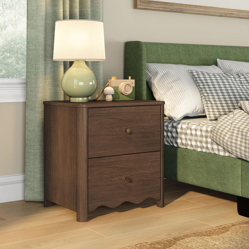 Brown wooden two-drawer nightstand with ceramic lamp and toy camera beside green upholstered bed with gray gingham bedding