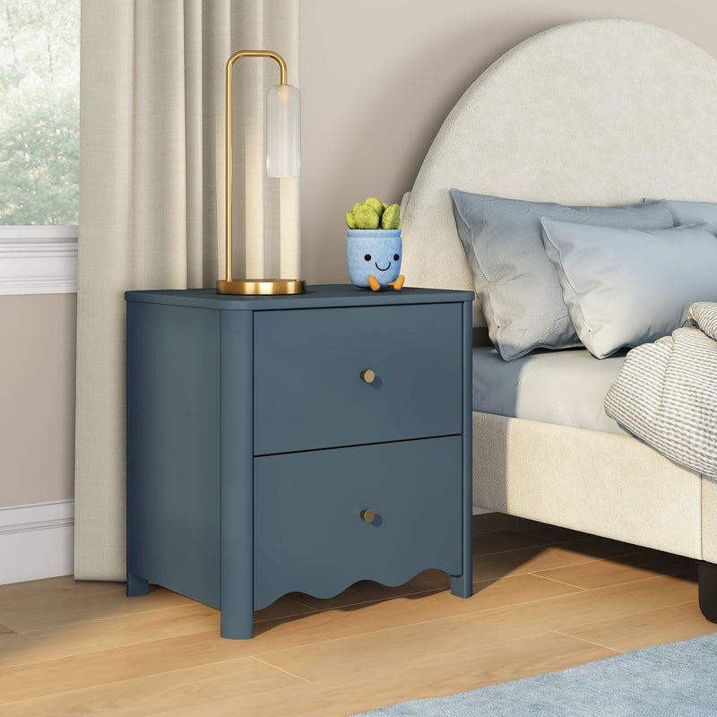 Modern navy blue two-drawer nightstand with gold-accent lamp and potted succulent beside upholstered bed on light wood floor in bright contemporary bedroom