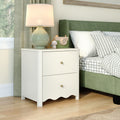 White two-drawer nightstand bedside table with scalloped trim, green ceramic lamp and wooden toy camera beside green upholstered bed with gray gingham bedding