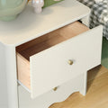 White nightstand with open drawer revealing wooden interior, brass knobs, green décor and checkered bedding