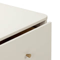 Close-up of cream bedside nightstand drawer with brass cone knob and rounded edge, minimalist modern bedroom furniture
